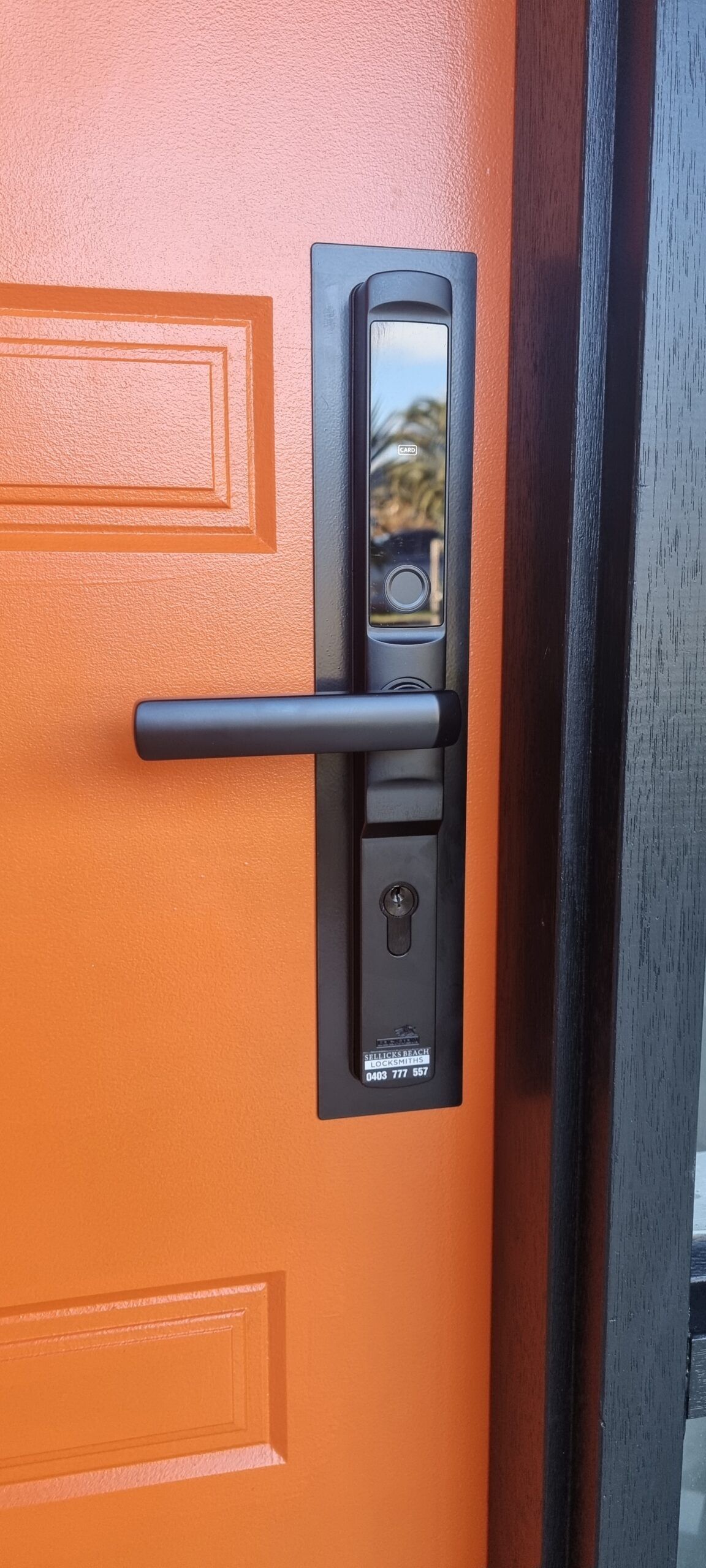 A fingerprint smart lock fitted to an orange front door
