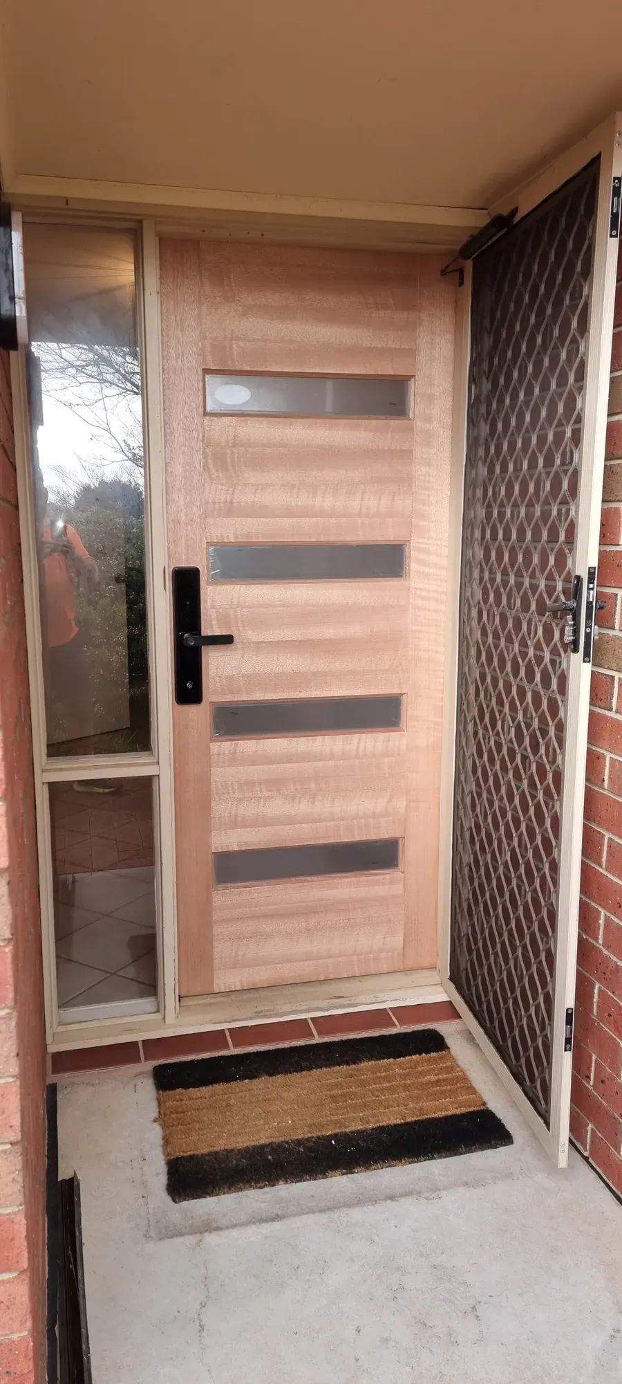 A black smart lock on a timber front door