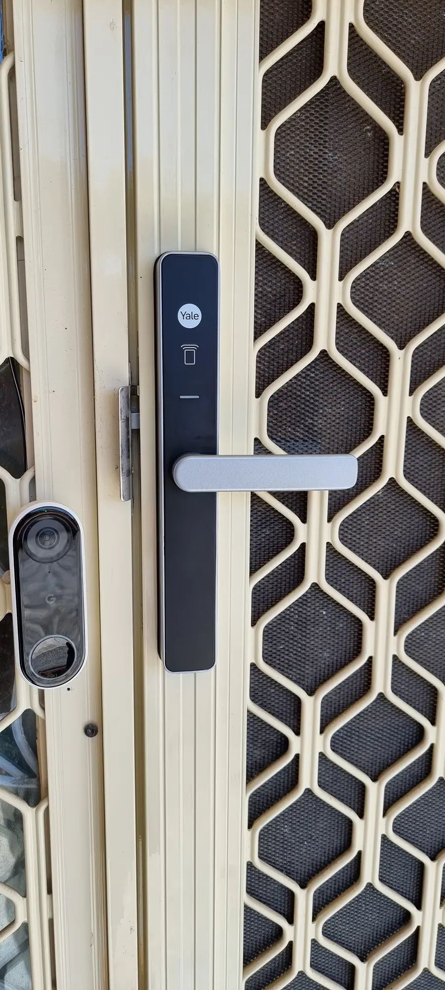 A slim smart lock and video doorbell on a security screen door
